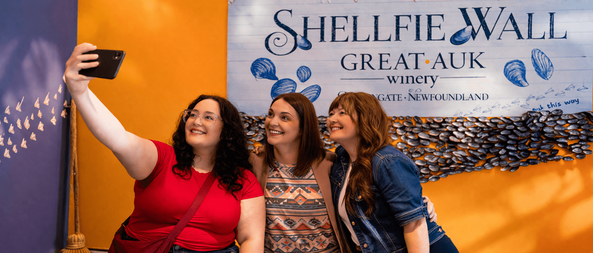Guests taking a selfie in front of the Shellfie Wall at Great Auk Winery